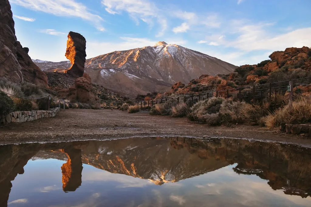 A captivating landscape of Mount Teide reflecting in a serene lake with rock formations.