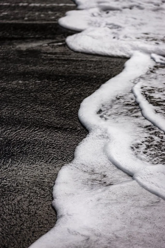 Artistic black and white shot of sea foam on a sandy beach in Santa Cruz de Tenerife.